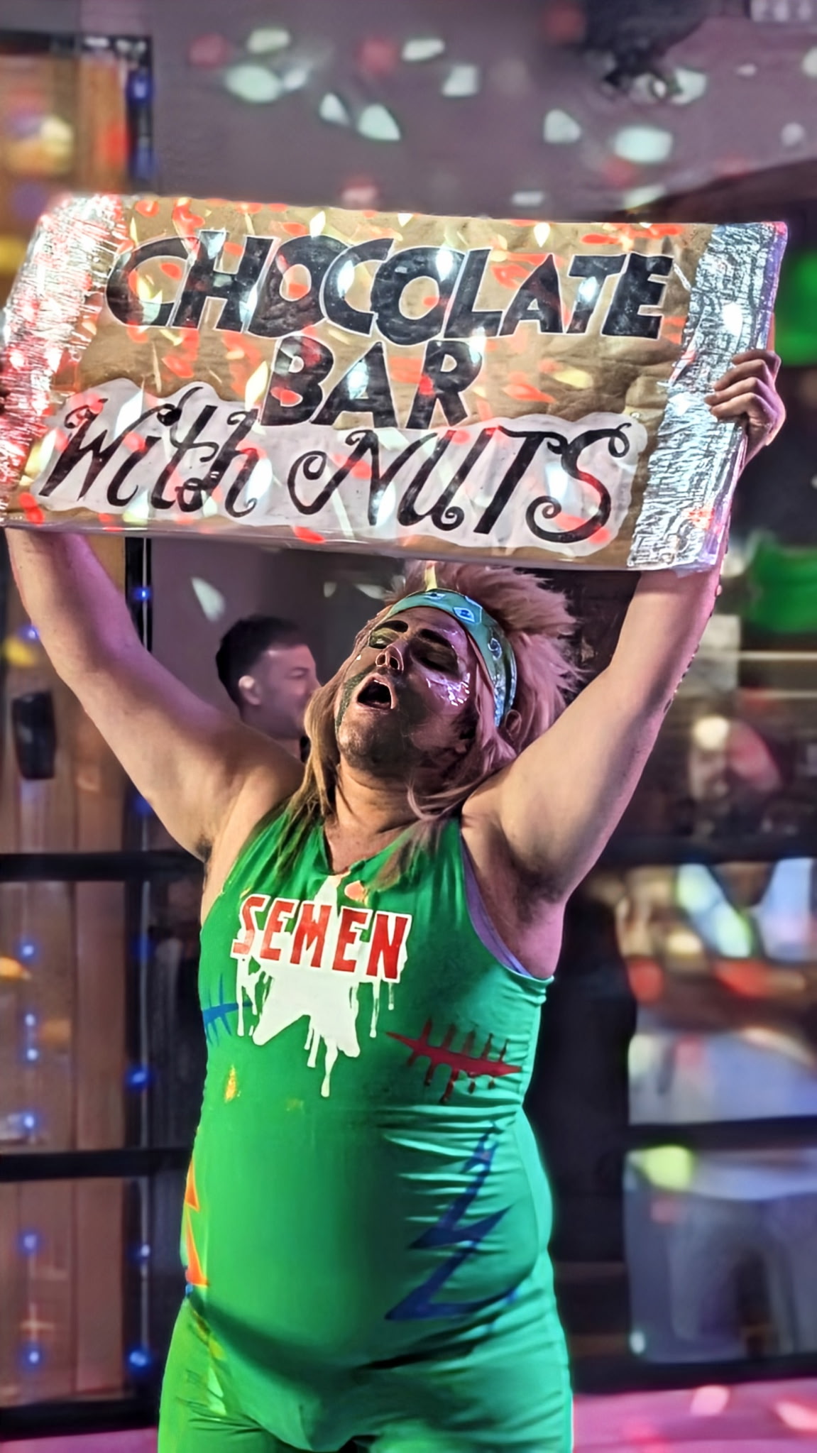 A performer raises a handmade Chocolate Bar Wild Nuts sign