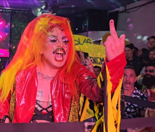 A fiery-haired wrestler gestures to the camera as the crowd reacts