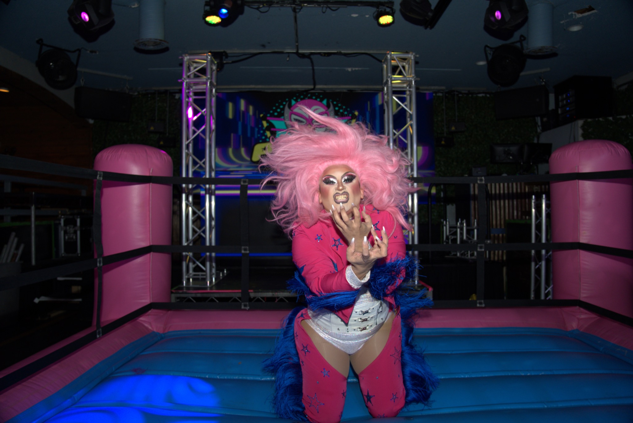 A pink-haired drag wrestler poses in the ring