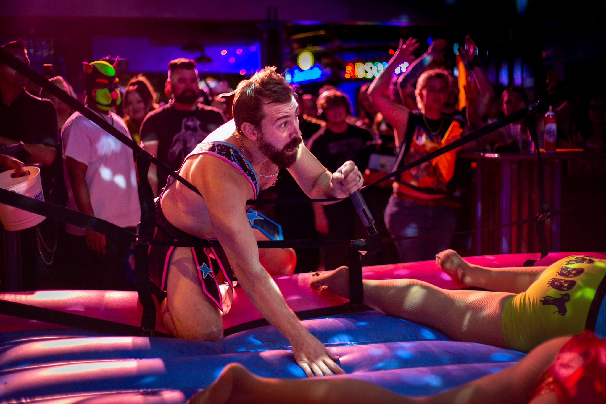 A wrestler reaches across the ring as the crowd reacts